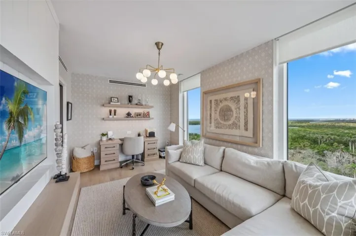 Living room with wood finished floors, wallpapered walls, a chandelier, and built in study area