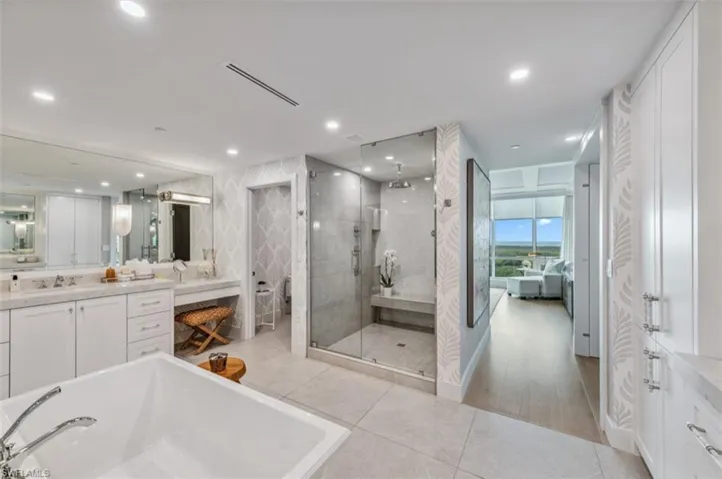 Ensuite bathroom with vanity, a stall shower, a freestanding tub, and light tile patterned floors