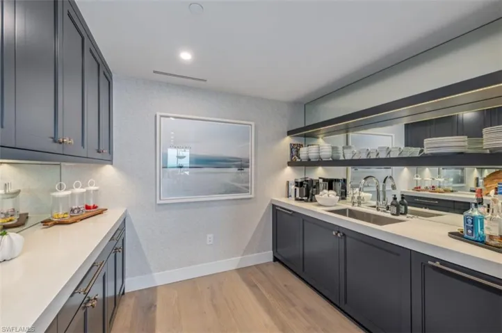 Bar area featuring light wood-style floors, gray cabinetry, light stone counters, and recessed lighting