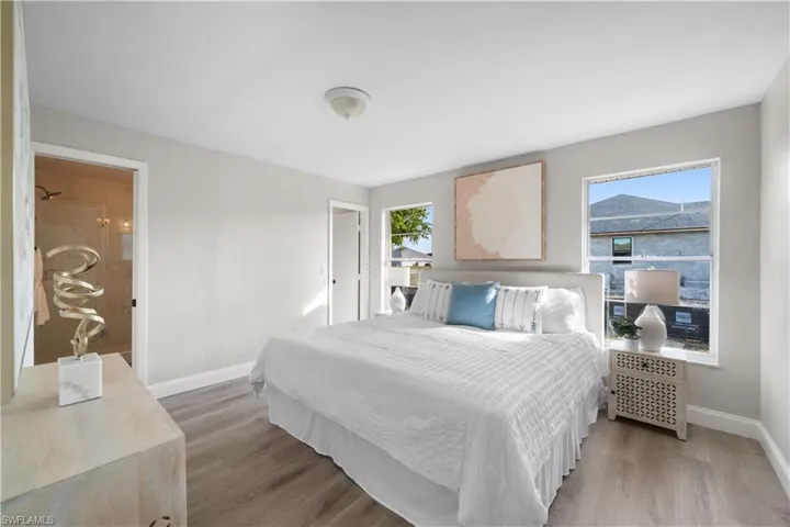 Bedroom featuring ensuite bath, hardwood / wood-style floors, and multiple windows