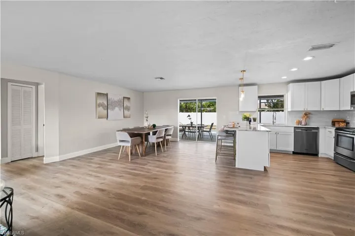 Kitchen featuring appliances with stainless steel finishes, hanging light fixtures, white cabinetry, and a kitchen island