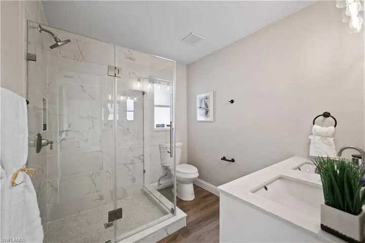Bathroom with toilet, wood-type flooring, vanity, and an enclosed shower