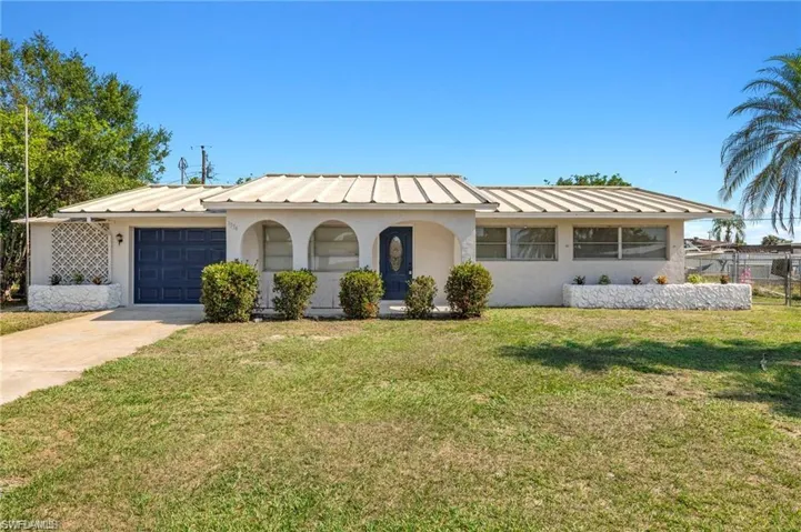 View of front of property featuring stucco siding, a standing seam roof, an attached garage, concrete driveway, and a metal roof
