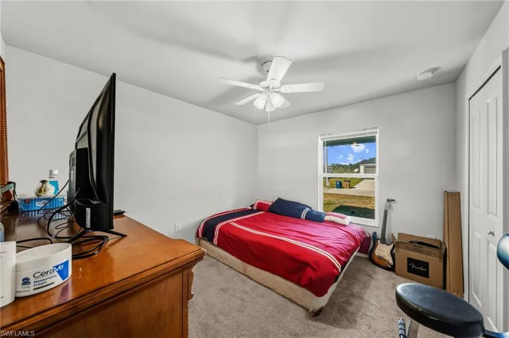 Carpeted bedroom with ceiling fan and a closet