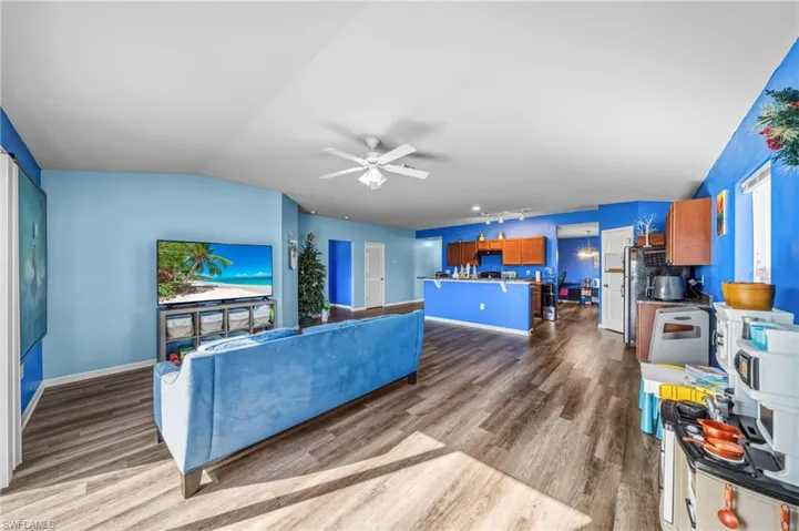 Living room with a ceiling fan, vaulted ceiling, and wood finished floors