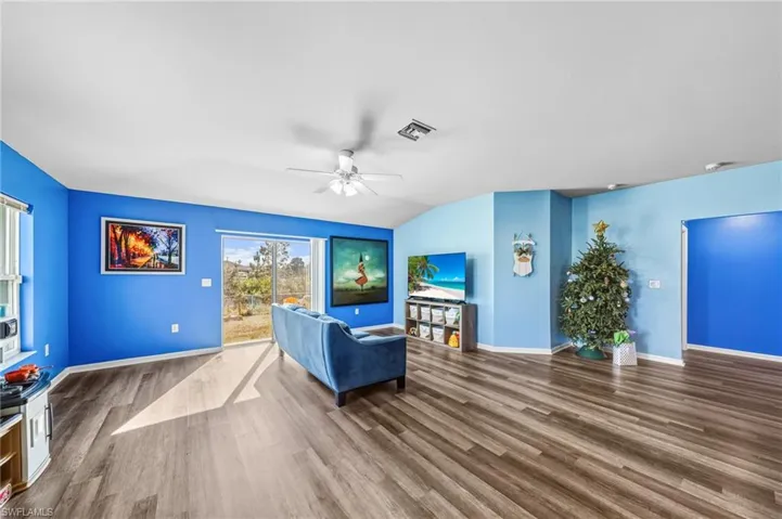 Living room with dark wood finished floors, a ceiling fan, and lofted ceiling