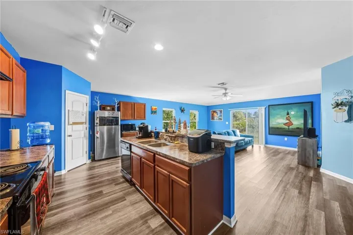 Kitchen featuring dark countertops, black appliances, dark wood finished floors, a ceiling fan, and brown cabinets