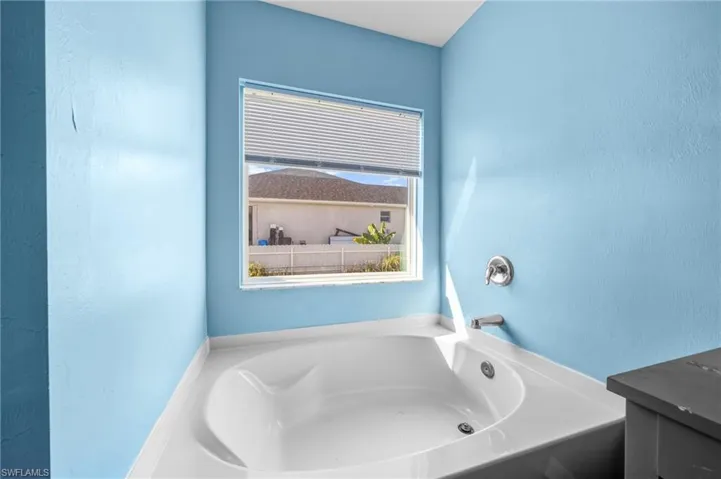 Full bathroom with a garden tub and a textured wall