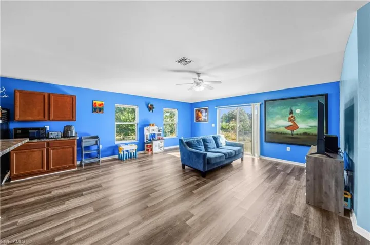 Living area featuring healthy amount of natural light, dark wood-style flooring, and ceiling fan