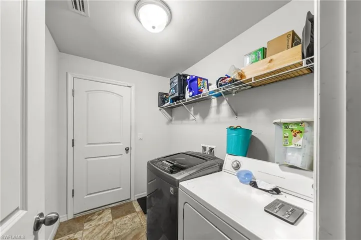 Washroom featuring washer and dryer and stone finish flooring