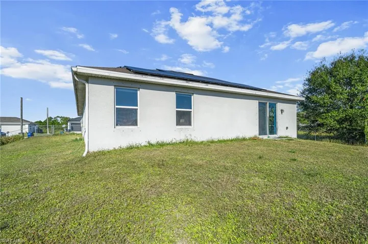 Back of property with solar panels and stucco siding