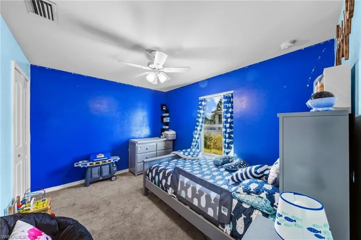 Carpeted bedroom featuring ceiling fan and a closet