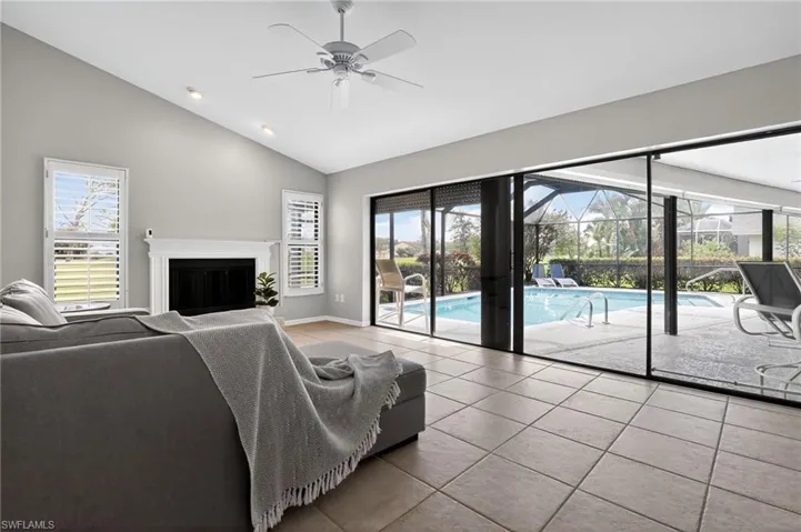 Living area with tile patterned flooring, a sunroom, a ceiling fan, a fireplace, and high vaulted ceiling