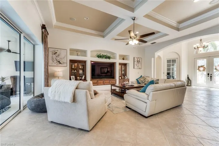 85" built in TV with premium sound bar in the great room. Entry foyer at right.