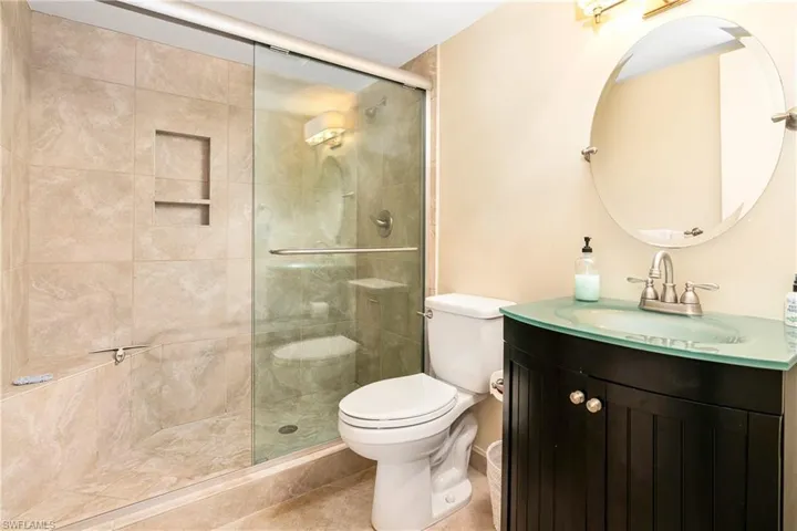 Bathroom featuring toilet, vanity, tile patterned flooring, and an enclosed shower