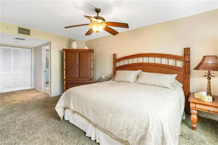Carpeted bedroom featuring ceiling fan and a closet