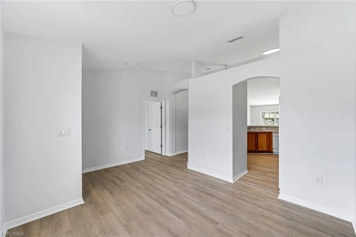Empty room with lofted ceiling and light wood-type flooring