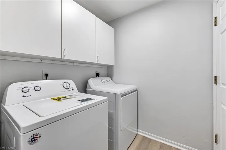 Laundry area featuring light wood-type flooring, cabinets, and washing machine and dryer