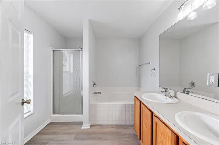Bathroom with vanity, wood-type flooring, and plus walk in shower