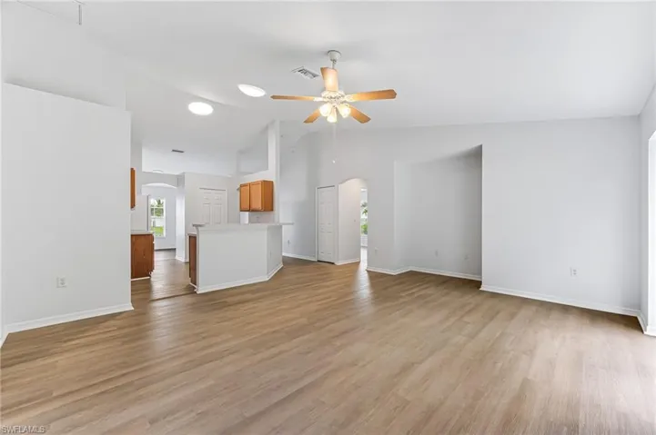 Unfurnished living room with light hardwood / wood-style flooring, ceiling fan, and high vaulted ceiling