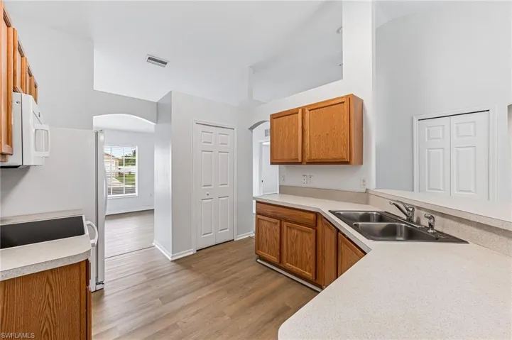 Kitchen with high vaulted ceiling, sink, and light hardwood / wood-style floors