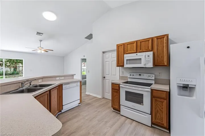 Kitchen featuring light hardwood / wood-style flooring, white appliances, plenty of natural light, and ceiling fan