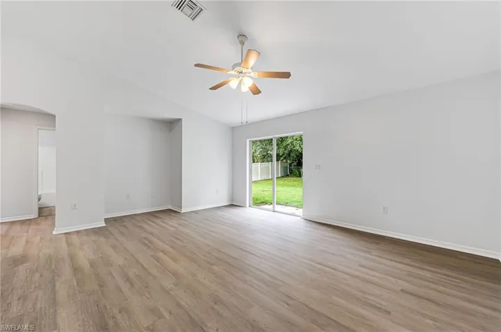 Empty room with high vaulted ceiling, wood-type flooring, and ceiling fan