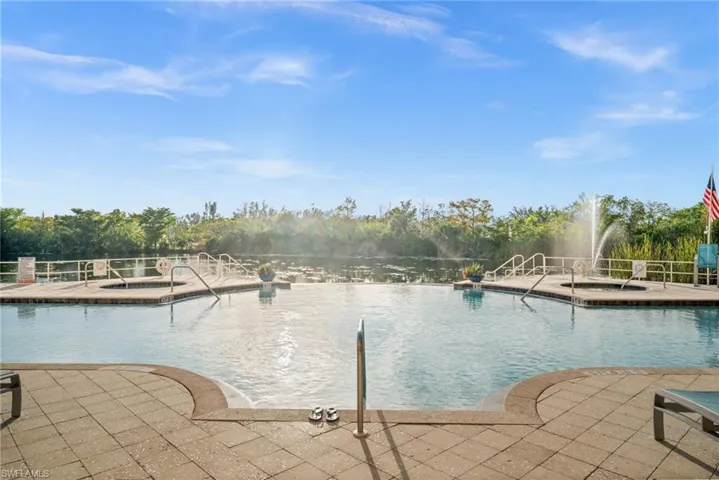 Community pool featuring a patio area and view of wooded area