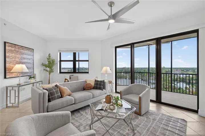 Living area with light tile patterned flooring, a water view, and a ceiling fan
