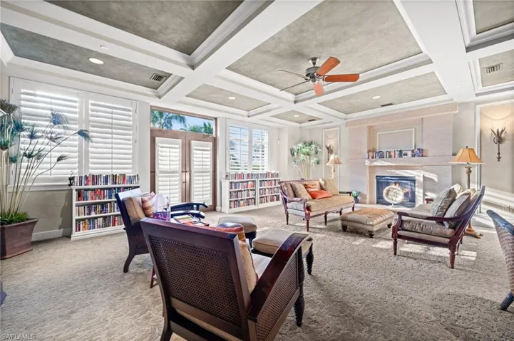 Carpeted living area with a high end fireplace, ceiling fan, and beam ceiling