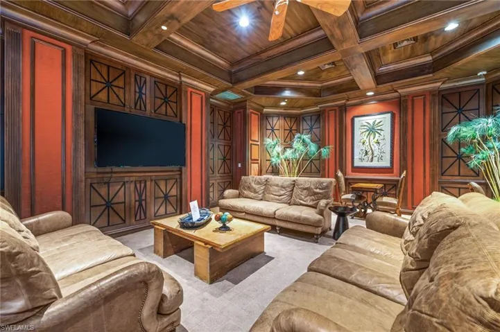 Living room with a wood ceiling with exposed beams, coffered ceiling, a decorative wall, ornamental molding, and wooden walls