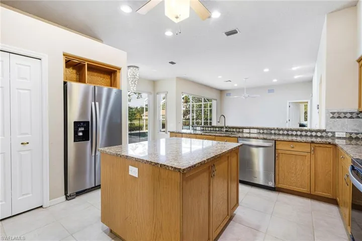 Kitchen with a kitchen island, ceiling fan, Granite counters, light tile floors, and Newer Stainless Steel Appliances