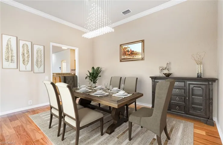 Dining room (Virtually Staged)with ornamental molding, a notable chandelier, and light hardwood flooring