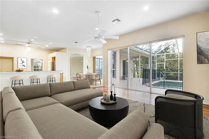 Virtually Staged Great Room with ceiling fan and Mahogany hardwood flooring Open to Kitchen with Granite Breakfast Bar and Breakfast Nook w/ Chandelier