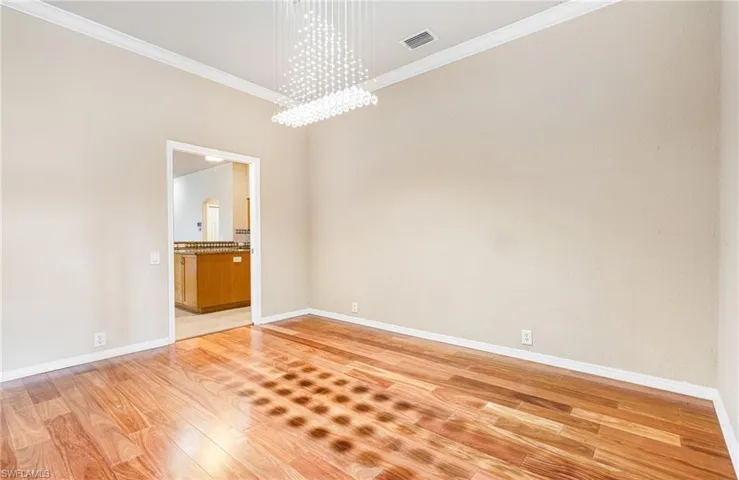 Formal Dining Room (unstaged) featuring a  Crystal chandelier, crown molding, and  Mahogany Hardwood floors