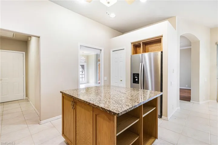 Kitchen with a kitchen island, ceiling fan, Granite counters, light tile floors, and Newer Stainless Steel Appliances