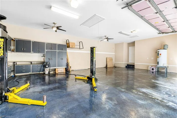 Garage with carl lift, workshop area with cabinets, ceiling fans and new water heater