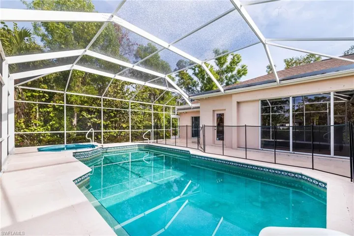 View of pool with a patio, an in ground hot tub, and glass enclosure