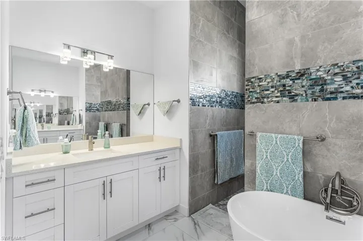 Bathroom with a bathing tub, vanity, and walk-thru shower.