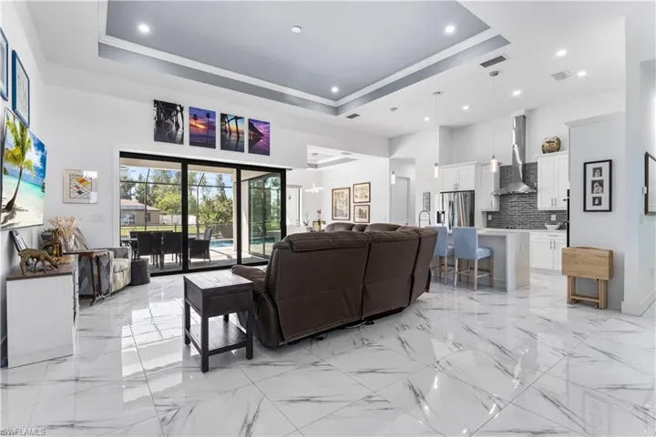 Living room featuring tile floors throughout, tray ceiling, open-concept living/kitchen/dining area.