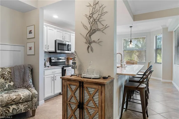 Kitchen with a breakfast bar, tasteful backsplash, light tile patterned floors, appliances with stainless steel finishes, and ornamental molding