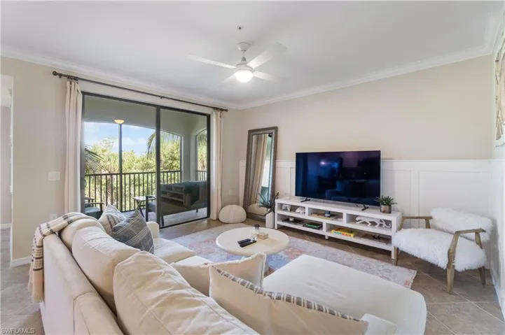 Living room with crown molding, ceiling fan, and light tile patterned floors