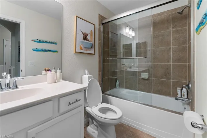 Full bathroom with tile patterned flooring, toilet, enclosed tub / shower combo, and vanity