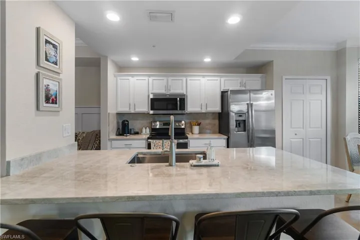 Kitchen with a breakfast bar area, ornamental molding, stainless steel appliances, and backsplash
