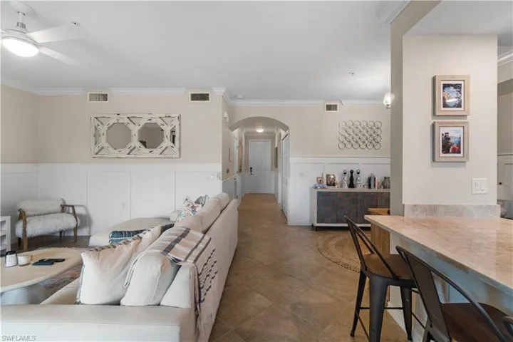 Tiled living room featuring ornamental molding and ceiling fan