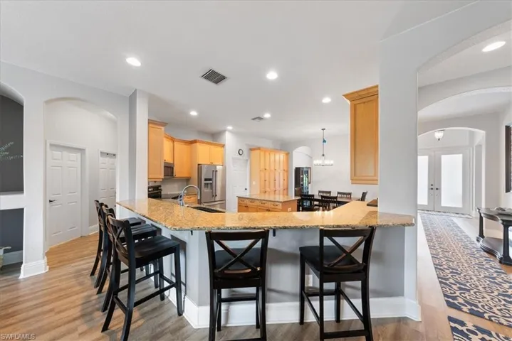 Kitchen with stainless steel appliances, hanging light fixtures, french doors, and light wood-type flooring