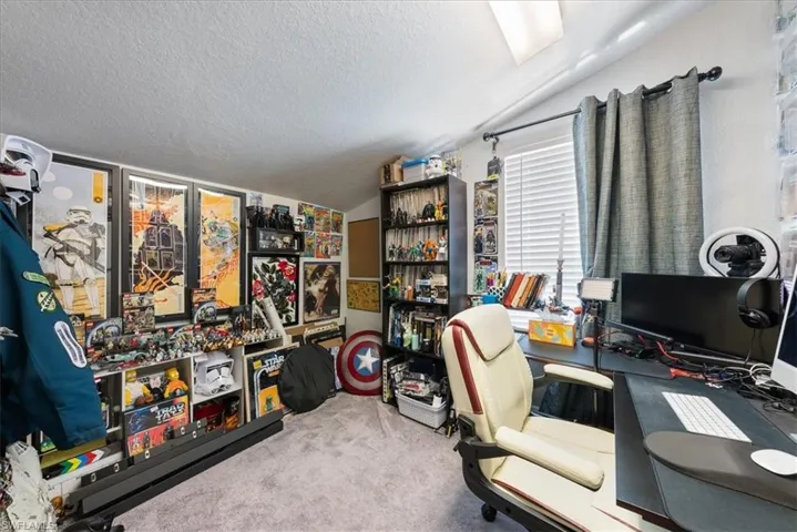 Carpeted home office featuring a textured ceiling and lofted ceiling