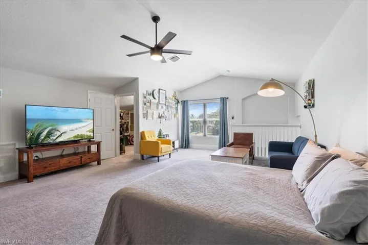 Carpeted bedroom with ceiling fan and lofted ceiling