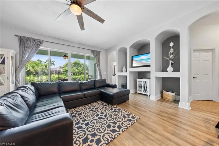 Living room with ceiling fan, built in features, and light hardwood / wood-style floors