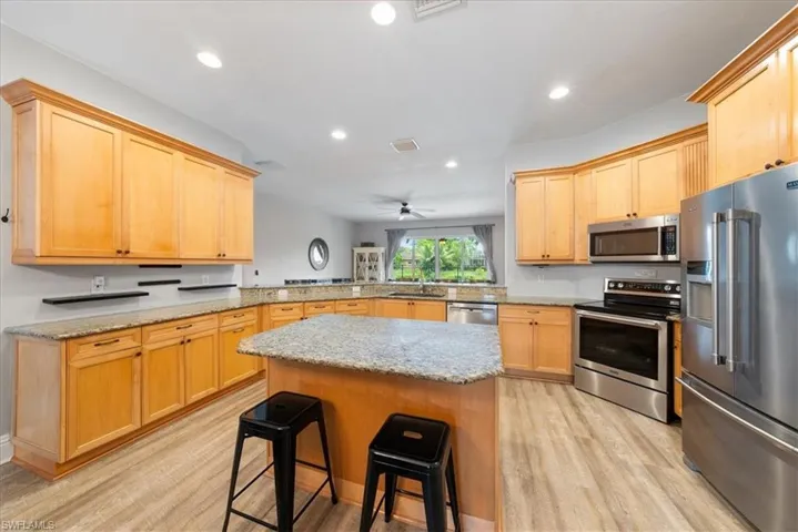 Kitchen with kitchen peninsula, a kitchen breakfast bar, ceiling fan, light wood-type flooring, and appliances with stainless steel finishes